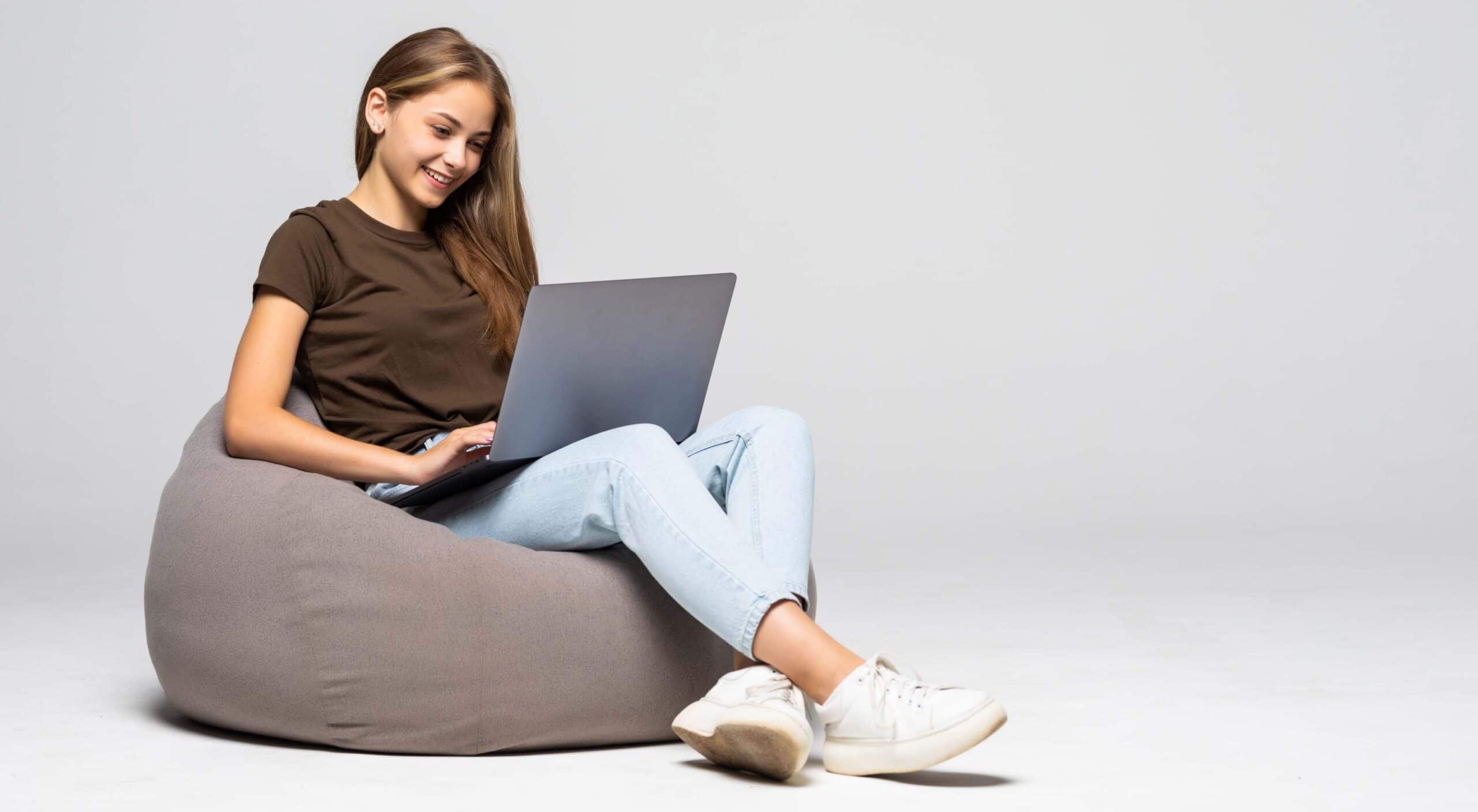 Woman sitting on a bean bag chair using her laptop
