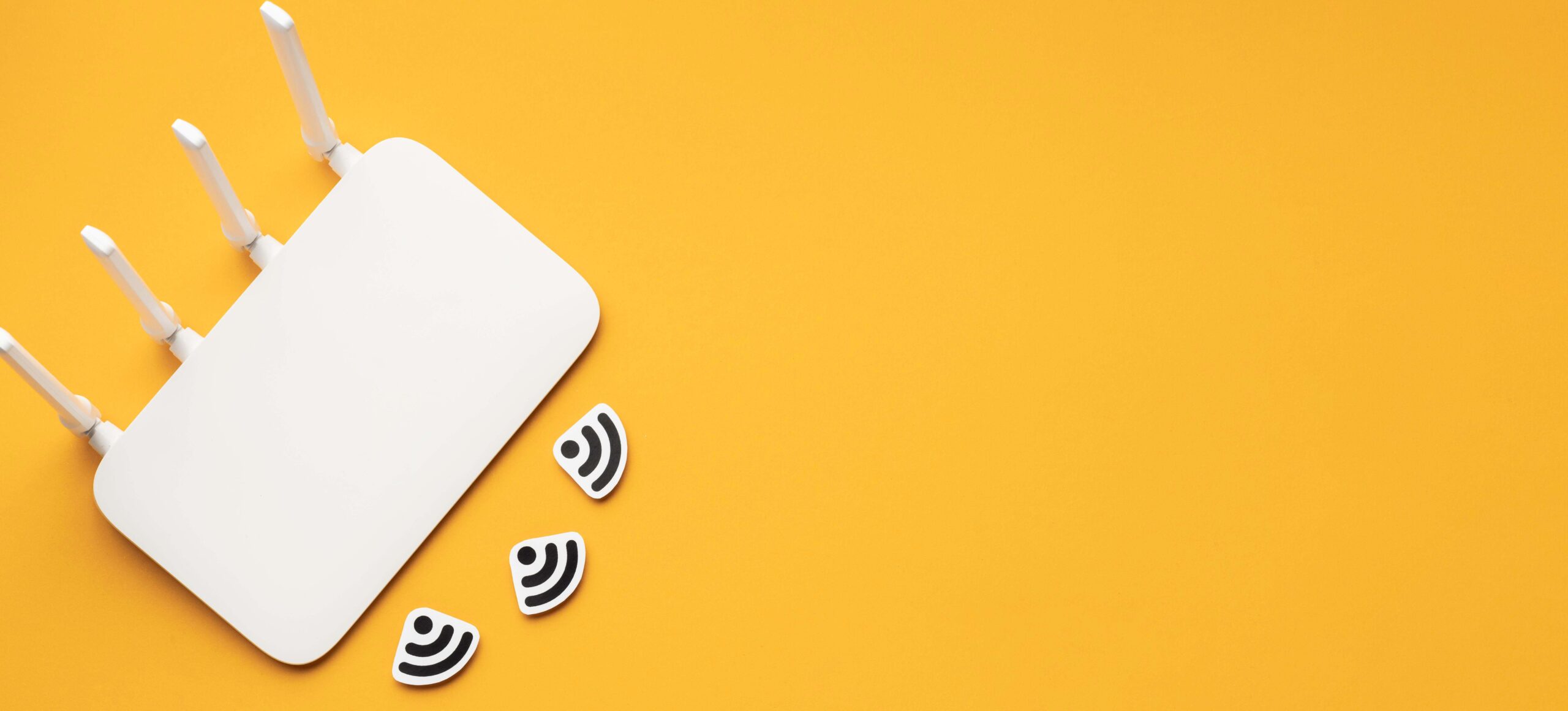 Overhead view of a white router with Wi-Fi symbols on a yellow surface.