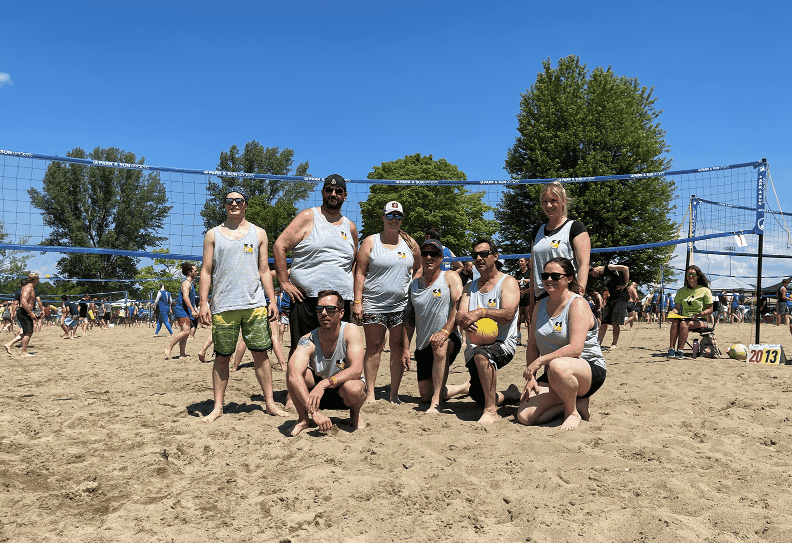 Group image of the Storm Internet team who participated in Hope Volleyball 2022. The team is standing on a sand beach court in front of a volleyball net.